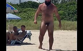 Urso barbudo desfilando na praia de nudismo.